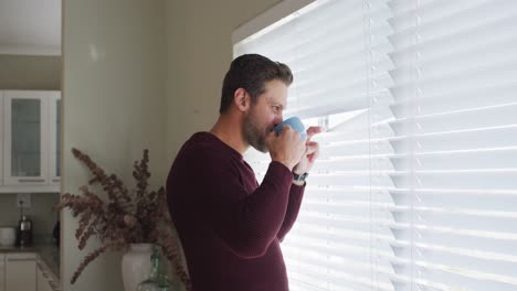 Video-Eines-Nachdenklichen-Kaukasischen-Mannes,-Der-Kaffee-Trinkt-Und-Aus-Dem-Fenster-Schaut