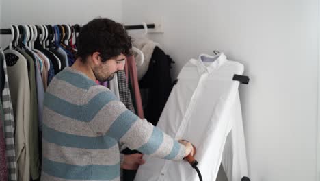 joven planchando su camisa en casa