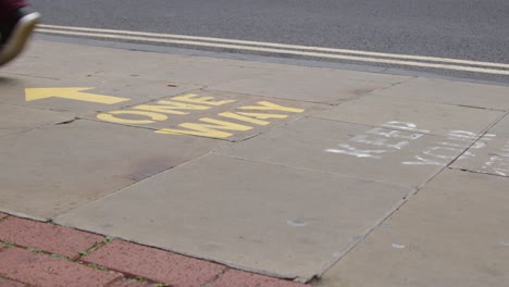 Close-Up-Shot-of-Pedestrians-Feet-Walking-Over-One-Way-Pavement-Marking-In-Oxford