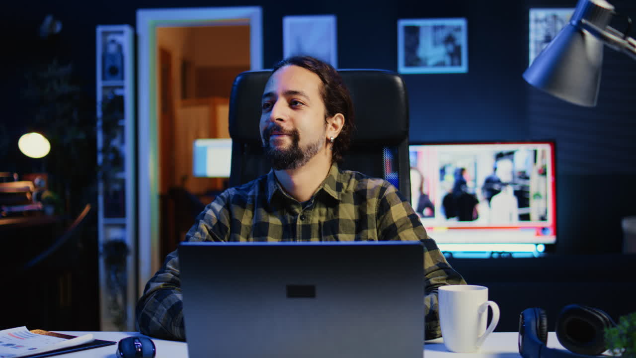 retrato de un hombre feliz sentado en el escritorio de la oficina de casa, resolviendo tareas en la computadora portátil