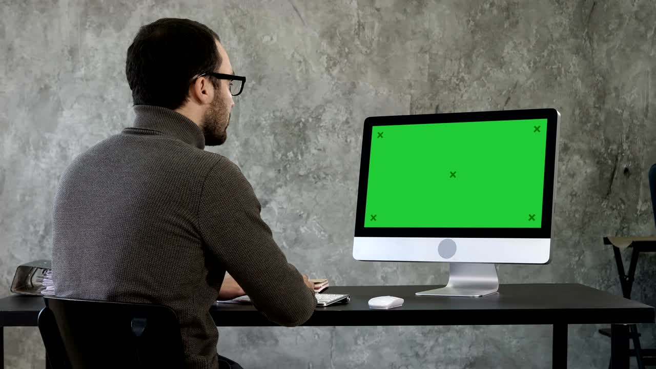 joven empresario barbudo despertando en la computadora. pantalla verde muestra de maqueta