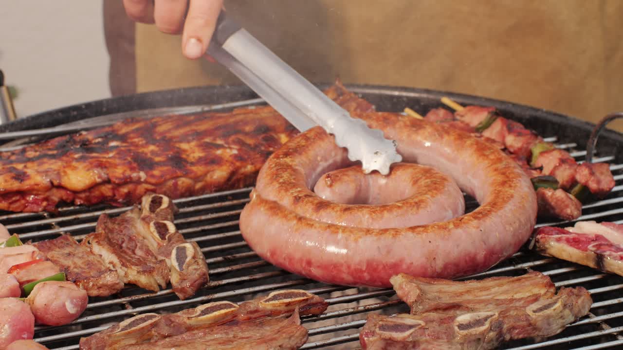 Traditional spanish barbeque, big sausage chorizo botifarra, pork and beef ribs on grill with fire, american style cooking, chef grilling meat fat food, steaks and sausages on bbq. High quality 4k footage