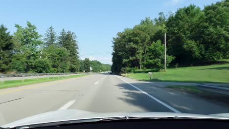 a quiet countryside road bordered by lush green trees and a bright blue sky. perfect for a scenic drive, this peaceful landscape offers a glimpse of nature's calm beauty.