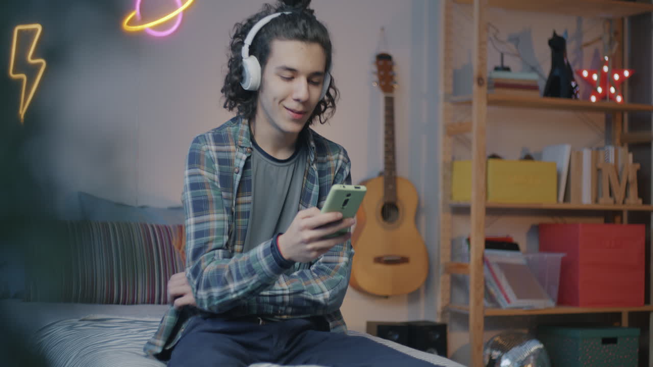 Teenager listening to music and using smartphone in bedroom