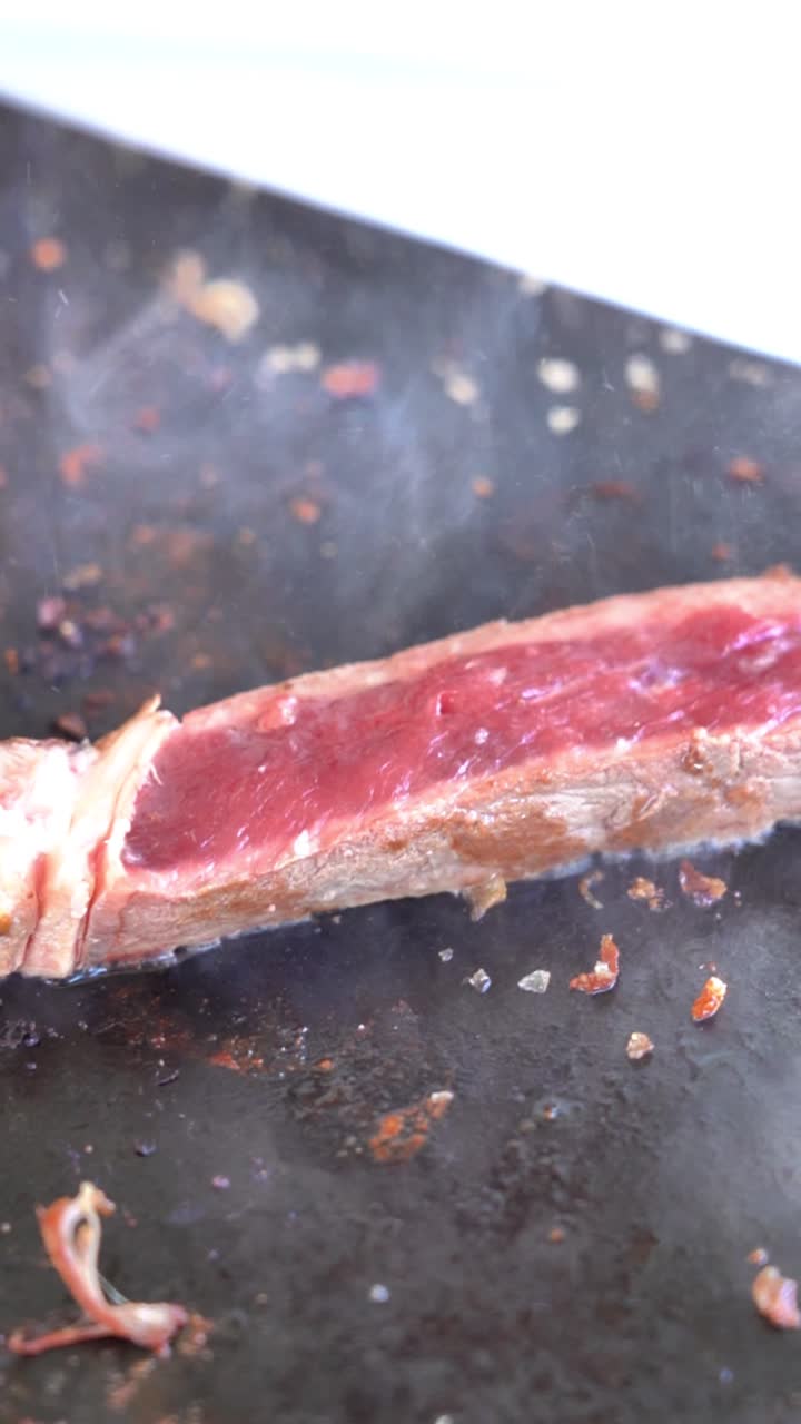 Si usa una forchetta per tagliare un pezzo di carne. La carne è su una superficie nera e ha della salsa sopra.