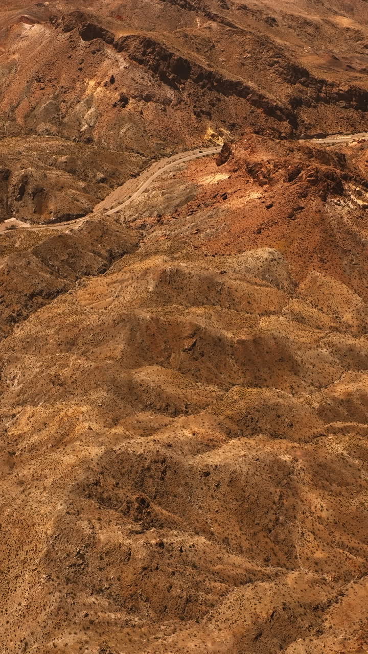 Brown dry landscape of Mojave desert. Rocky landscape with a highway in the middle. Top view. Vertical video