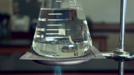 erlenmyer flask that is being heated by a bunsen burners no condensation left, heat waves visible in flask, bubbles forming