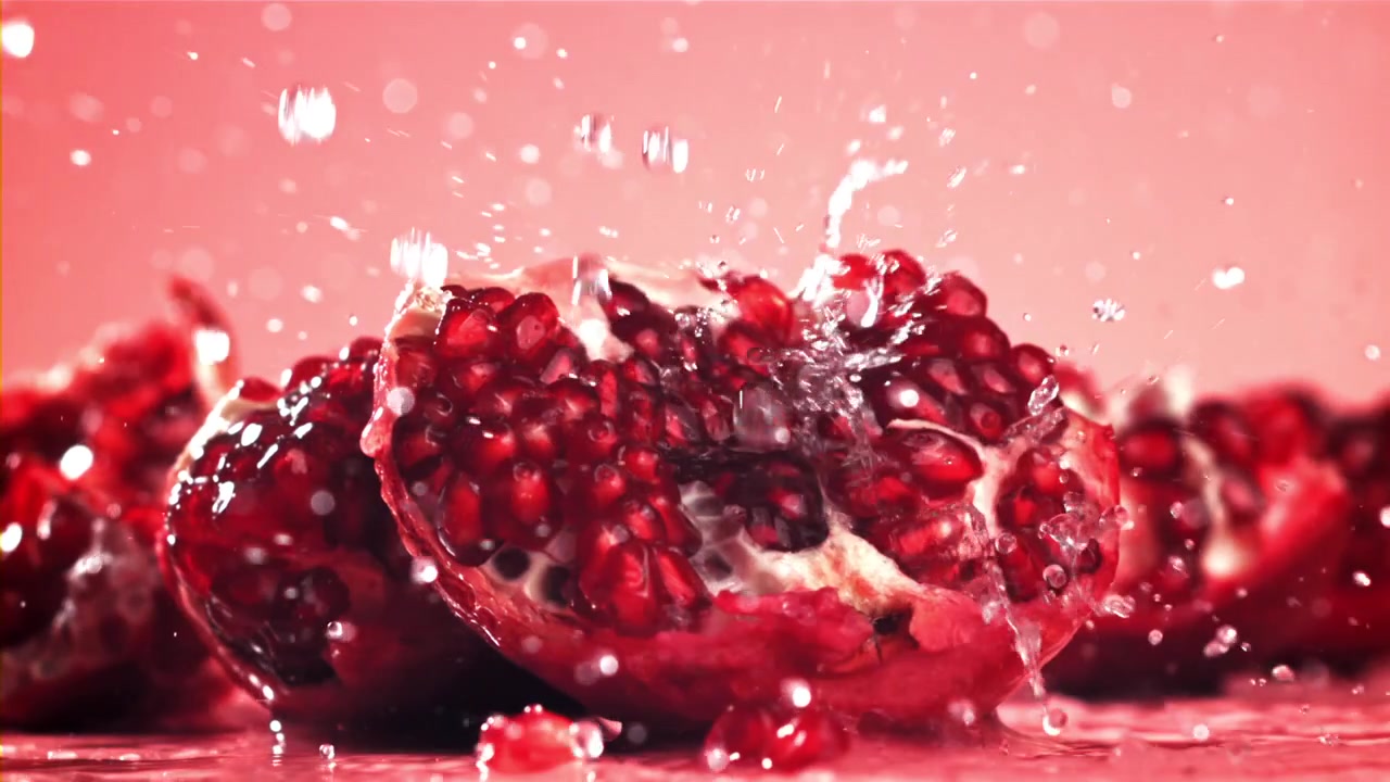 Slow motion vandplask på friske røde granatæblehalvdele