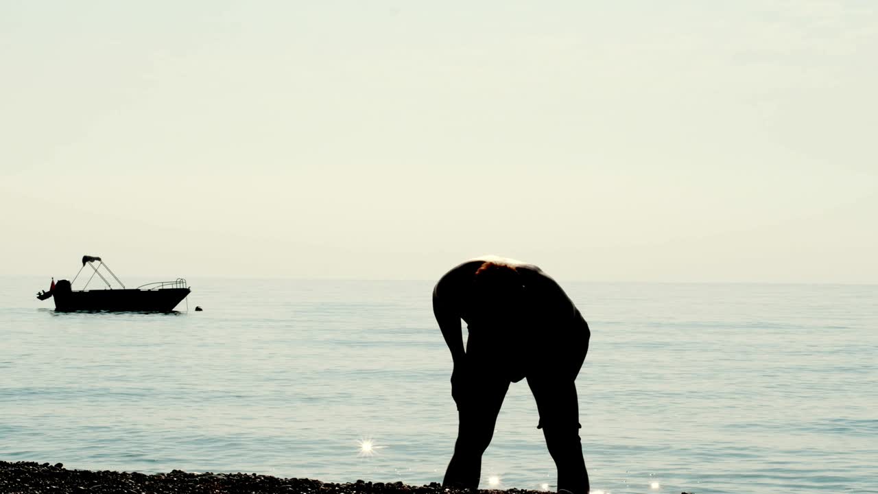 Active young man doing physical exercise near ocean. Man doing exercise for body