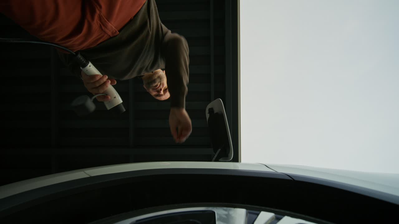 차고에서 전기 차량을 충전하는 사람