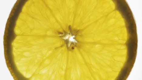rotación de una rebanada de naranja transparente sobre un fondo blanco.