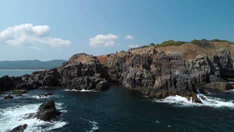 Toma-Aérea-De-Grandes-Rocas-En-El-Mar-Junto-A-La-Orilla-En-Un-Día-Soleado-De-Verano