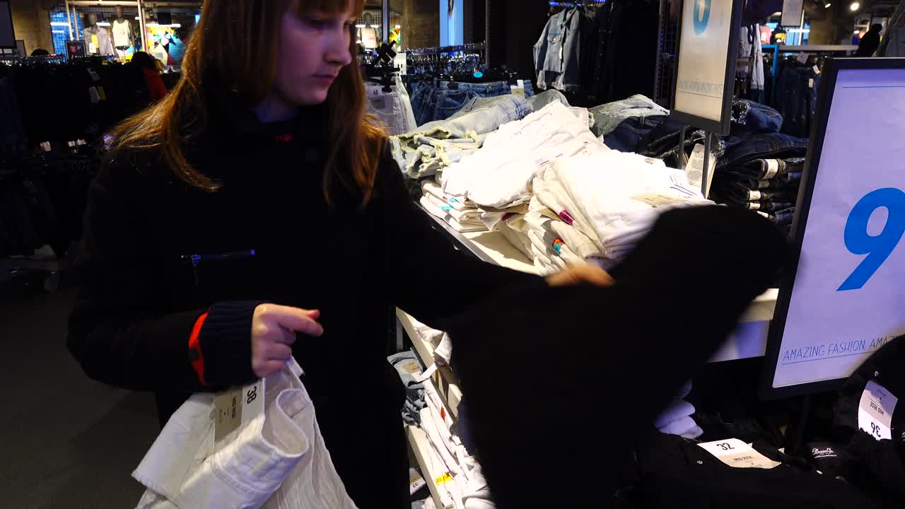Shopping negli outlet in Europa. La ragazza sceglie i vestiti. Saldi e sconti