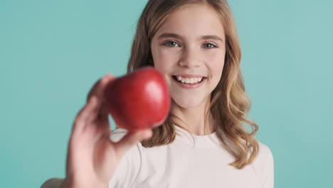 Teenage-Caucasian-girl-in-pijamas-holding-an-apple-and-smiling.