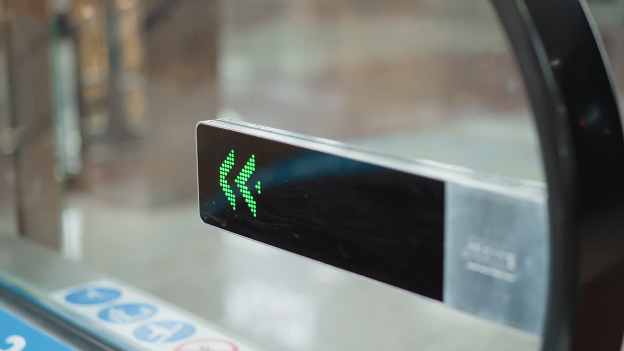 close up of green led arrow display mounted on escalator side indicating leftward direction in modern mall terminal under bright ambient lighting next to glass barrier with glossy floor reflection