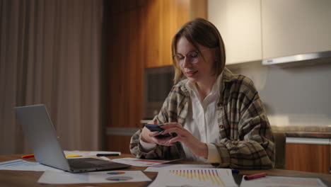 mujer de negocios con un teléfono inteligente moderno enviando mensajes de texto en la oficina. mujer joven empleada usando una aplicación de negocios de tecnología móvil moderna escribiendo correo electrónico en el celular sentada en el escritorio de trabajo.