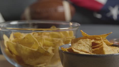 sala de estar en casa de una persona viendo un partido de fútbol americano en la televisión con bebidas, bocadillos y pelota 3