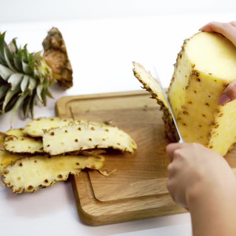 peeling pineapple on a cutting board. female's hands cleaning fresh exotic fruit with a knife. tropical food.