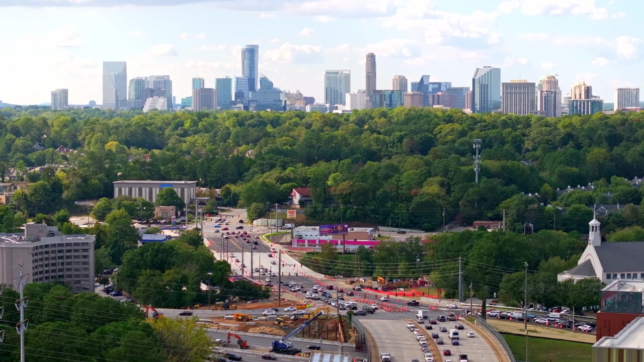 Cantiere stradale urbano in asfalto, coni spartitraffico, escavatori e gru sulla strada, strada North Druid Hills con edifici di Buckhead Atlanta in vista, Georgia