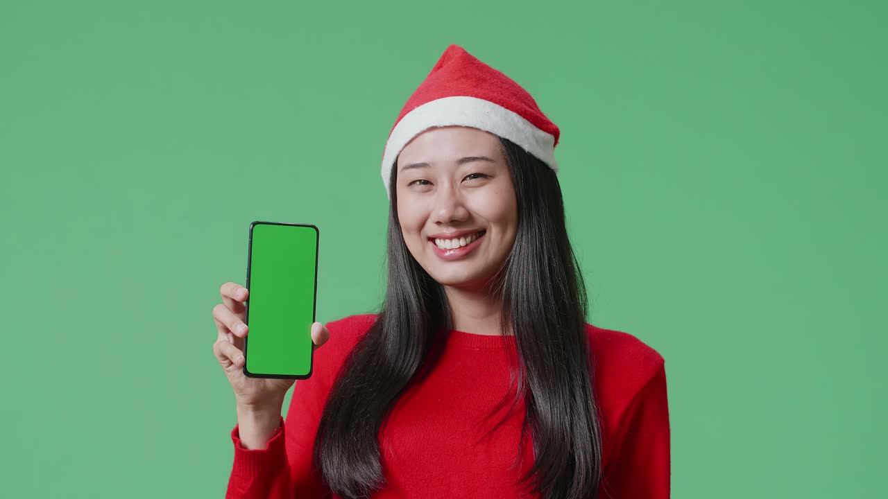 녹색 화면 을 가진 스마트폰 을 들고 있는 산타 모자 를 입은 여자