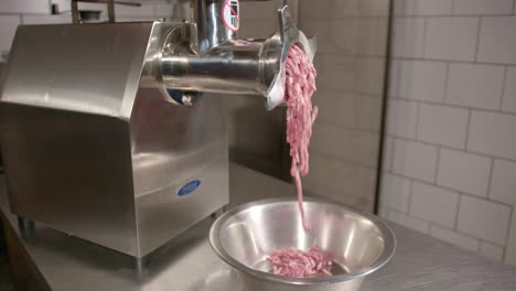 fresh raw meat being minced in a metal grinding machine, close up