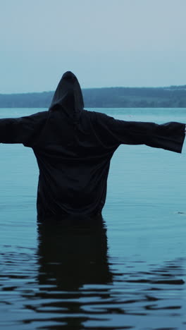 female figure in a black robe in the river. divination in the night of halloween. vertical video