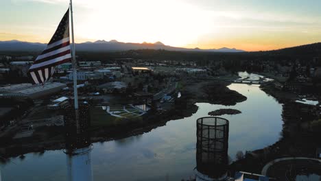 Drone-shot-of-the-American-flag-waving-over-the-Old-Mill-District-in-Bend,-Oregon