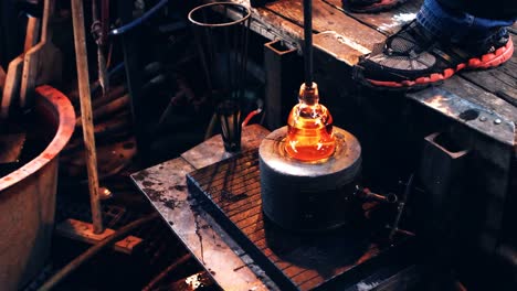 glassblower using mold to shape a molten glass