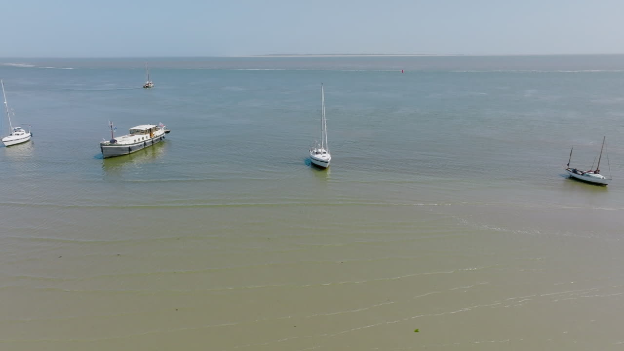A group of boats anchored at low tide on the bottom of the Wadden Sea on a sunny day. The Netherlands