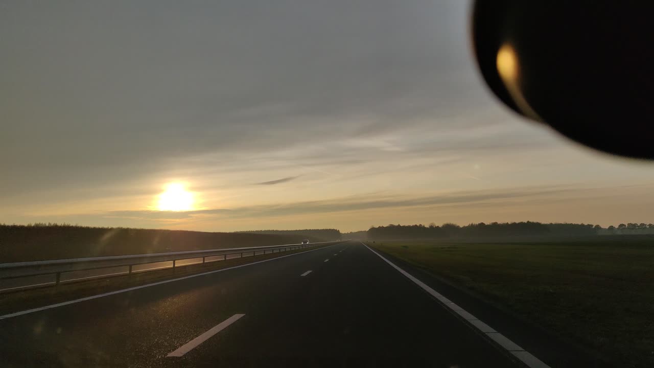 네덜란드 드렌테에서 일몰 동안 n33 고속도로를 운전하는 자동차 앞 유리 밖을 내다보고 있습니다.