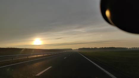 looking out of car windshield driving down the n33 highway during sunset in drenthe the netherlands