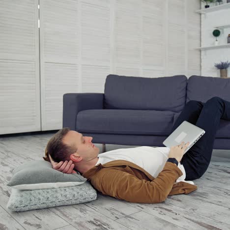 freelancer works on laptop on floor. tired young businessman lying on a floor and puts aside the laptop after the long job at home. distant job during quarantine