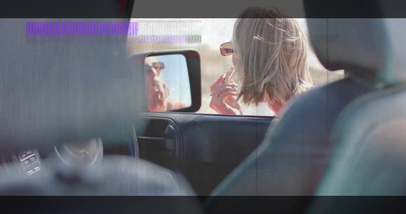 Donna che prende il rossetto allo specchietto dell'auto, applicandolo, controllando il colore tra sovrapposizioni con effetto glitch per la bellezza
