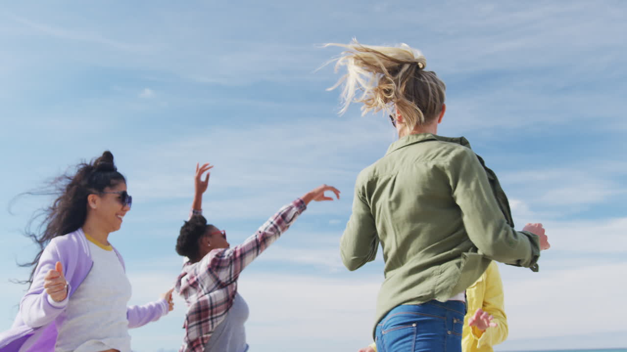 un grupo feliz de amigas diversas divirtiéndose, bailando y sonriendo en la playa