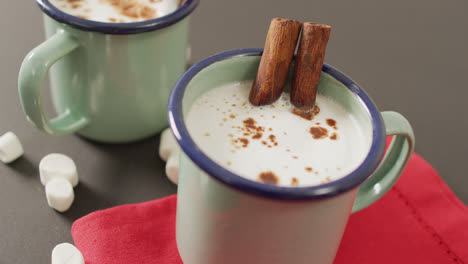 video of cups of hot chocolate with cinnamon over grey background