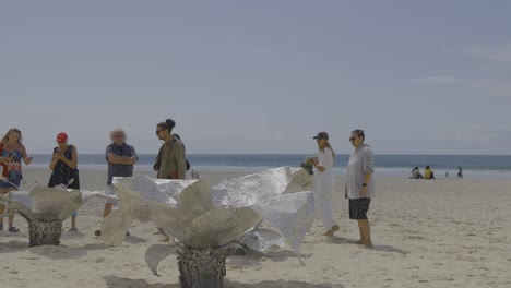 people observing a sculpture on the beach