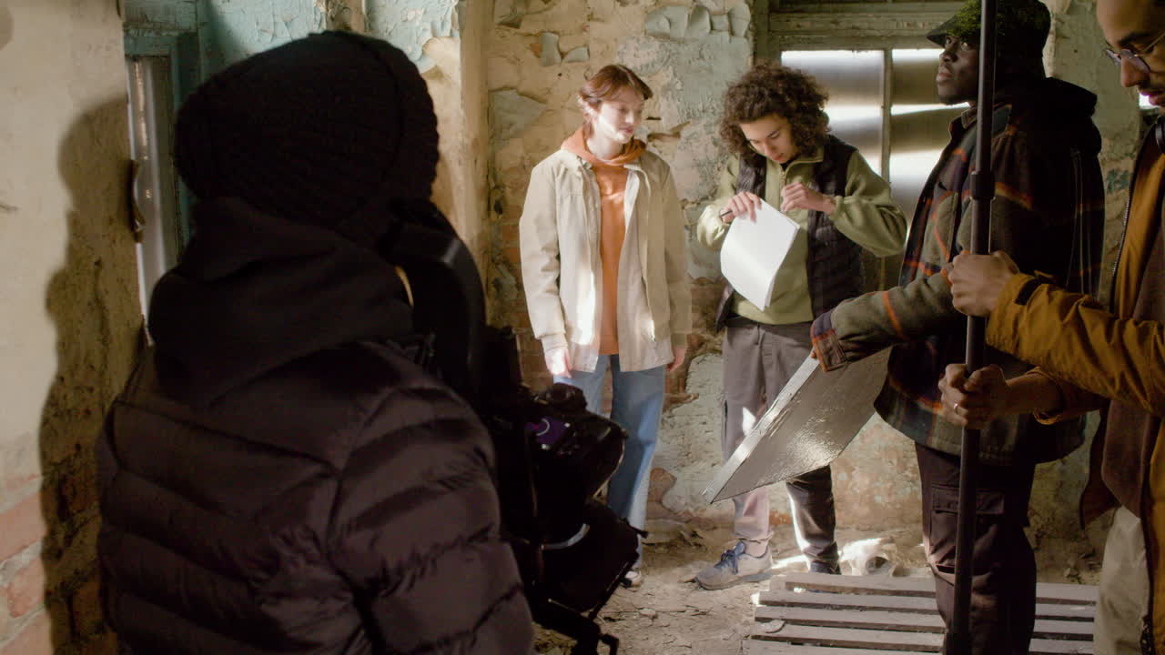 вид сзади на оператора, снимающего своих коллег в разрушенном здании