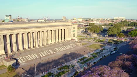 órbita aérea de la facultad de derecho de la uba con una protesta escribiendo en las escaleras &quot;reforma judicial transfeminista&quot; al atardecer en una zona turística del barrio retiro