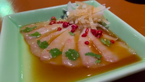 Delicioso-Sashimi-De-Atún-Blanco-Con-Chile-En-Un-Plato-En-Un-Restaurante-Japonés,-Pescado-Crudo,-Cocina-Asiática,-Toma-De-4k