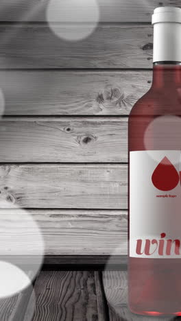 animación de luces sobre botella y vaso de vino de rosa sobre fondo de madera