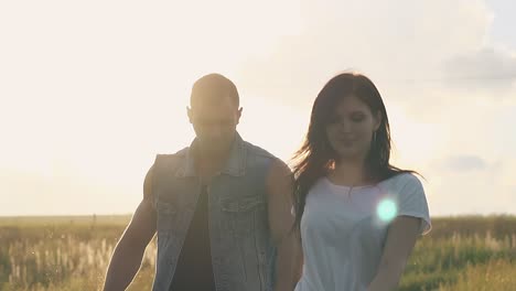 close-view-young-couple-silhouette-lit-by-sun-walks-on-field