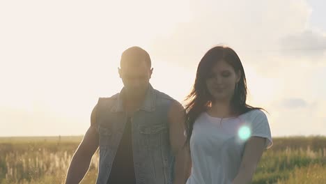 vista cercana silueta de una pareja joven iluminada por el sol camina por el campo