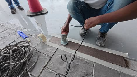 uneven concrete patching is being ground smooth by a construction worker using an electric grinder. safety is the top priority for this meticulous work.
