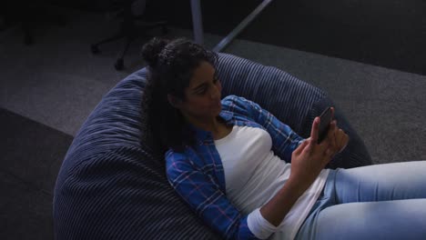 mixed race woman lying on bean bag taking selfie and smiling