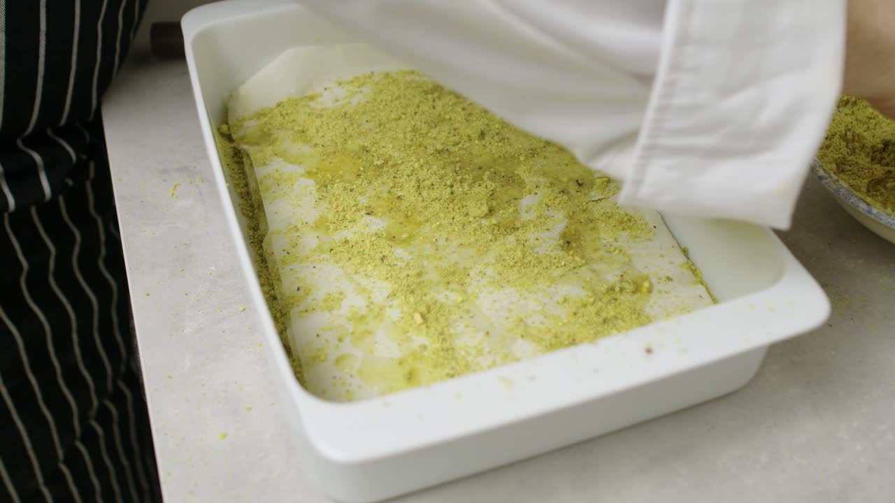 Time-lapse of putting baklava layers and ingredients inside ceramic pan