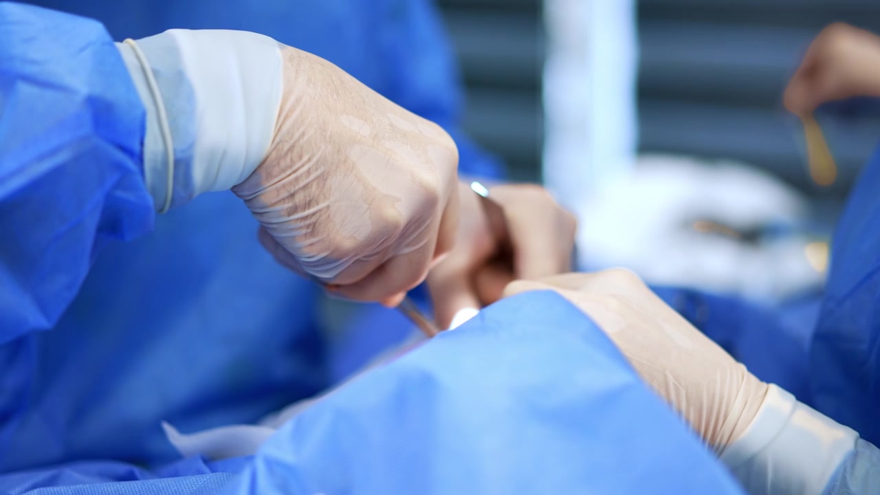 Mani di chirurgo e infermiera con guanti bianchi in lattice. Il medico utilizza strumenti metallici durante un intervento di chirurgia plastica. Primo piano