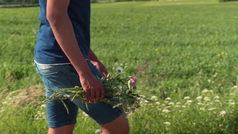 un joven con ropa informal de verano sostiene un ramo de flores, un día soleado