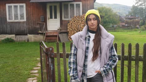 young woman in front of a rustic wooden house