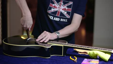 Restringing-and-cleaning-a-beautiful-black-single-cutaway-accoustic-guitar---using-pliers-to-remove-the-plugs-locking-the-strings-in-pace