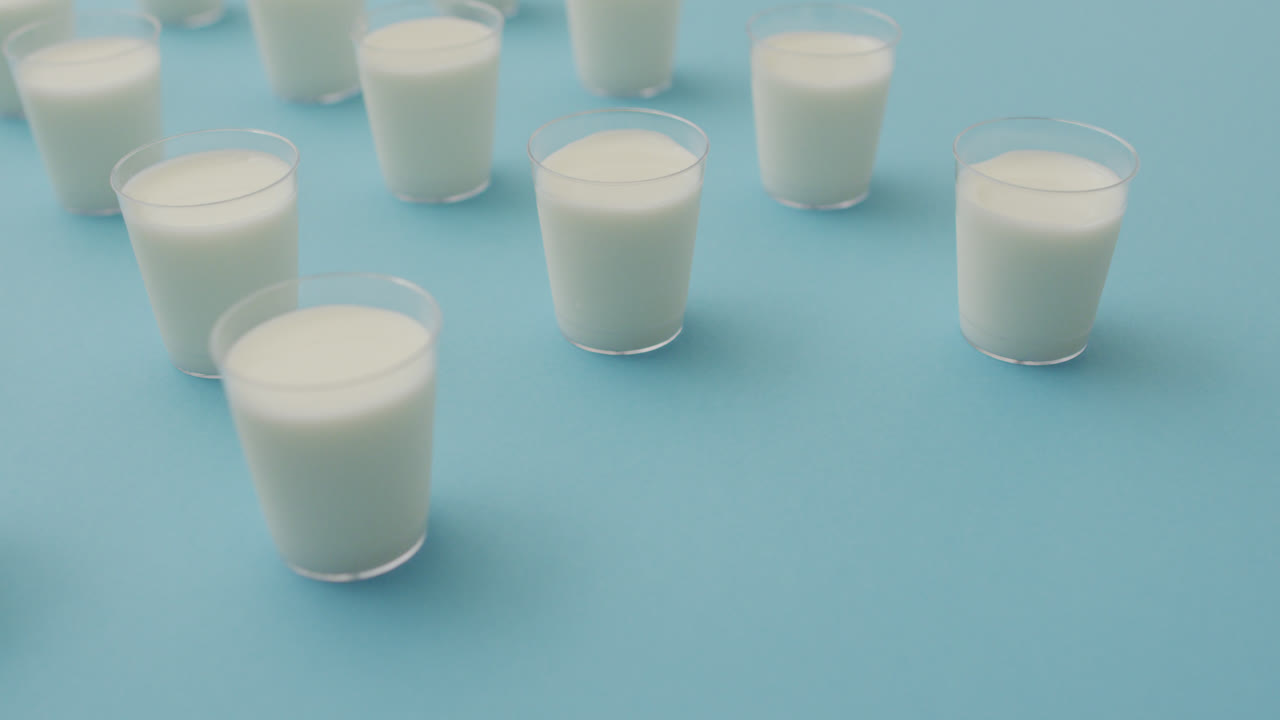 video de una fila de vasos de leche sobre un fondo azul